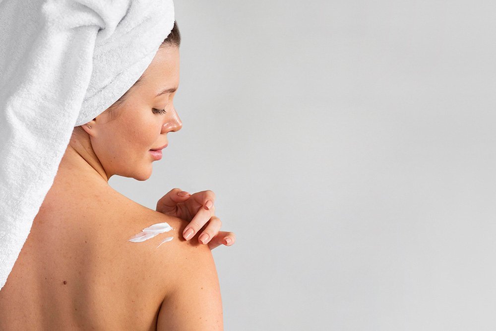 mujer aplicando crema corporal