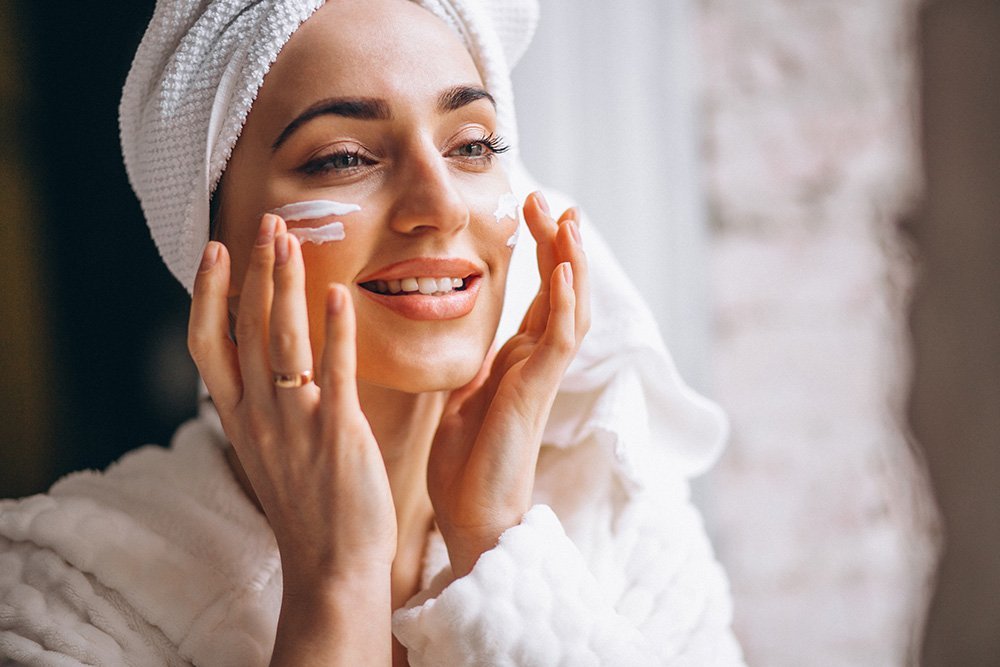 mujer aplicando crema en su rostro